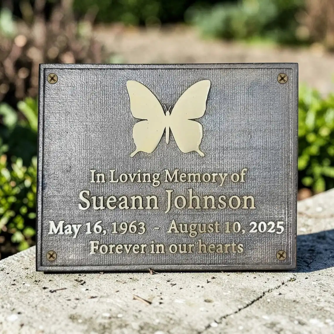 Memorial plaque with butterfly design and engraved text outdoors