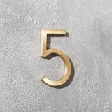 Modern solid brass house numbers featuring concealed stud mounting for a clean floating appearance.